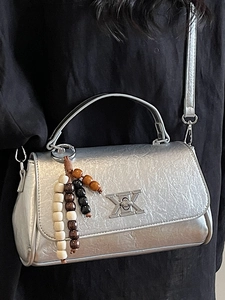 Sac bandoulière argenté métallisé avec poignée courbée et breloque en perles