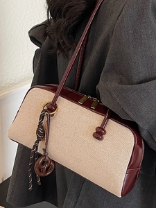 Beige canvas and burgundy leather underarm bag with striped knot charm on shoulder