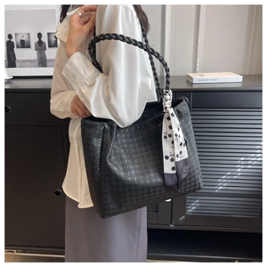 Detail view of black houndstooth embossed tote bag with woven handles and decorative scarf