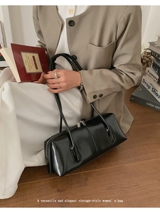 Dettaglio di una borsa a tracolla vintage in pelle nera lucida tenuta da una modella in interno