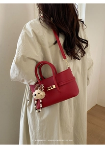 Detail of red pebbled leather handbag with gold hardware and polka dot bear charm