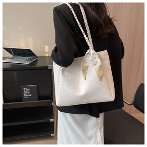 Detailed view of white textured tote bag with braided strap and polka dot silk scarf