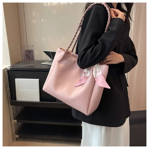 Detail of pink embossed tote bag with floral scarf handle worn on a black blazer