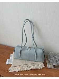 Dettaglio della borsa blu vintage con doppia cerniera posata su tavolo di legno