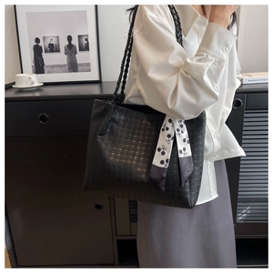 Detail of black PU leather tote bag with embossed texture and cherry pattern silk scarf