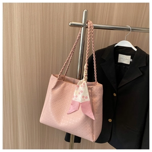 Detailed view of pink embossed leather tote bag with woven handles and silk scarf detail