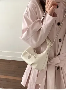 Detail of off-white crescent bag with scrunchie handle, bow design, and heart charm