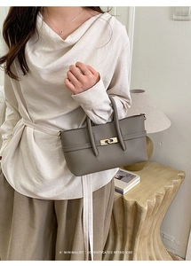 Close-up of gray-brown litchi grain leather bag with a golden twist-lock metal buckle