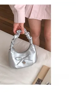 Detail of silver crescent moon bag featuring a bow, heart pendant, and scrunchie handle