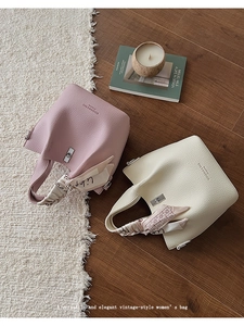 Detailed macro of textured leather bucket bags with elegant silk scarf wrap handles
