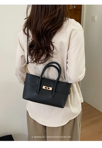 Detail showing retro black leather handbag with golden ring clasp and lychee texture