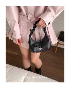 Detail of black pleated handle hobo bag with bow decoration and heart charm on model