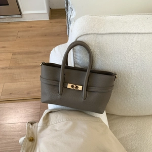 Detail of taupe pebbled leather tote featuring gold twist-lock and dual handles