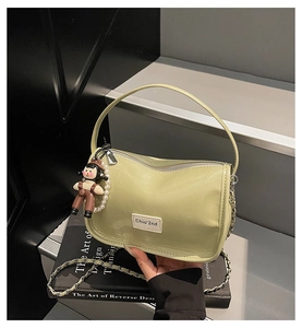 Détail du sac cylindrique vert avocat en cuir verni plissé avec bandoulière chaîne