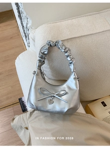 Detail of silver metallic textured bucket bag with scrunchie handle and heart charm