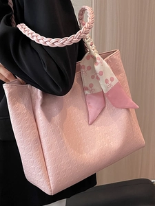 Pink houndstooth embossed tote bag with woven handles and floral scarf detail