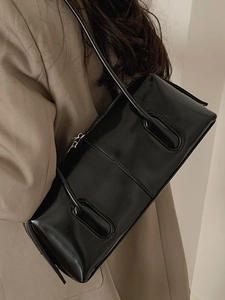 Borsa sottobraccio nera lucida con cerniera abbinata a un trench beige raffinato