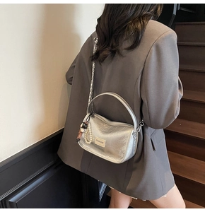 Détail du sac à main argenté métallisé avec chaîne, breloque perle et pendentif ours