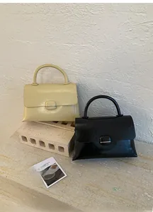 Detail of cream and black shiny wrinkled leather handbags on stone and textured wall