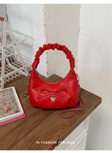 Detail of red PU leather bucket bag with cloud handle, bow knot, and heart pendant