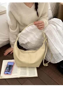 Detail of a creamy beige hobo bag with a minimalist design in a soft interior setting