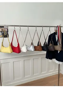 Multiple colorful PU leather shoulder bags hanging in a row showing various color options