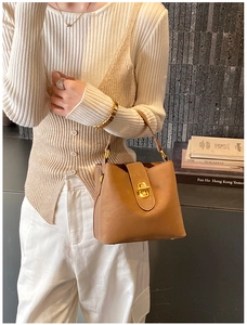 Detailed shot of brown leather bucket bag with elegant gold metal twist-lock buckle