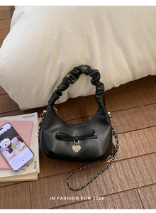 Detail of black PU leather bucket bag with ribbon bow, heart charm and pleated handle
