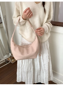 Pink crescent moon shoulder bag paired with beige knitwear and white pleated skirt