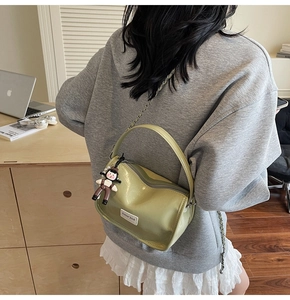 Détail du sac à bandoulière vert pistache avec chaîne en métal et breloque poupée