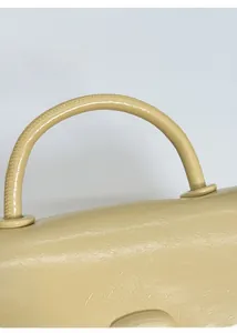 Detailed close-up of beige square bag thickened handle and polished metal buckle