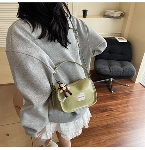 Vue détaillée du sac en cuir vert avocat avec breloque perle et bandoulière chaîne
