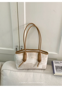 Détail du cabas en toile avec motif géométrique beige et breloques de nœuds en cuir brun
