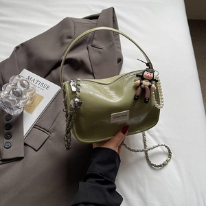 Détail d'un sac à main en cuir verni vert avec chaîne dorée et breloques de sac chic