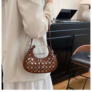 Vista dettagliata di una borsa a mezzaluna in pelle marrone con borchie argentate e doppia zip