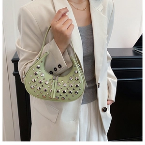 Dettaglio di una borsa a mezzaluna verde con borchie argentate e zip metallica