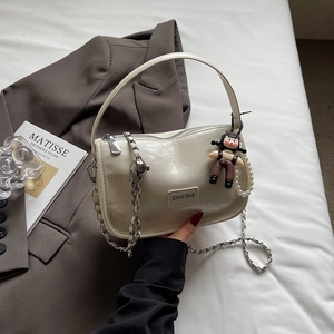 Détail du sac en cuir blanc crème avec chaîne argentée et breloque perle élégante