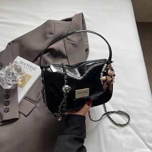Détail d'un sac à bandoulière noir brillant plissé avec chaîne et breloque perle