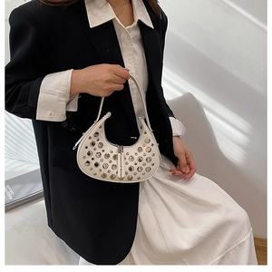 Dettaglio della borsa a mezzaluna bianca con borchie argentate e texture in pelle di qualità