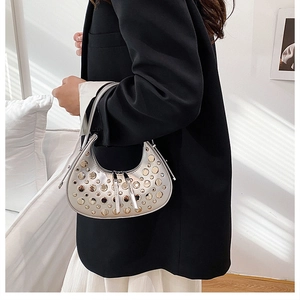 Dettaglio di una borsa a mezzaluna argentata con borchie metalliche tonde e cerniera
