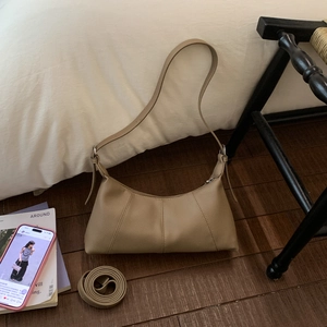 Detail showing the textured lychee leather and adjustable strap of the brown shoulder bag