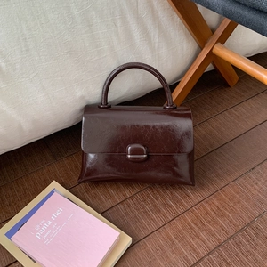 Detailed view of dark brown oil wax leather handbag with arc handle and vintage clasp