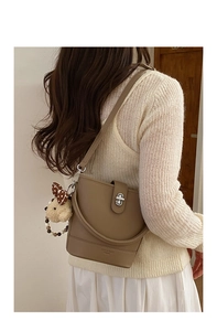 Detail of khaki leather bucket bag with rotating silver lock and plush bear charm