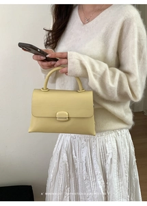 Chic pale yellow leather handbag with round top handle shown against a minimal background