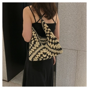 Detail of the crochet woven shoulder bag featuring black and beige geometric patterns
