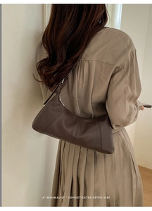 Detail view of brown pebbled leather texture and silver buckle on a minimalist hobo bag