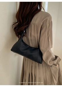 Detail view of black lychee grain dumpling bag with vertical seams on model shoulder