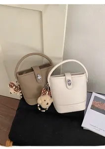 Close-up of litchi grain leather bucket bags with metal locks and cute bear charms
