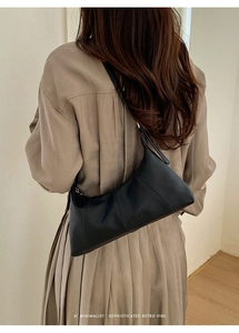 Close-up of black lychee grain leather shoulder bag worn by model in a minimal setting