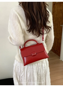 Detailed view of red patent leather handbag showing sleek flap and metallic clasp detail